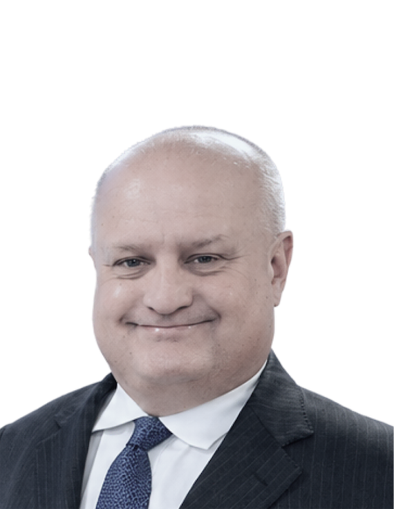 Smiling man in a dark suit and blue tie, head-and-shoulders portrait.
